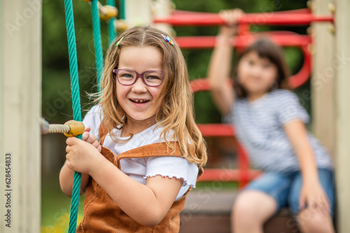 portrait of children, a happy smiling girl of 11 years old and a girl of 6 years old playing on a children's playground. looking at the camera close-up. High quality photo
