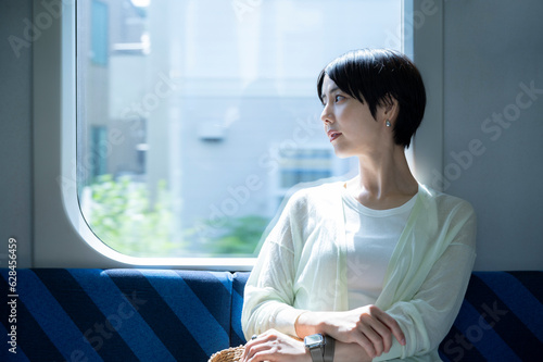 Fotografía An Asian woman sits on a train seat and looks out the window