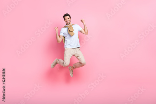Full body cadre of jump positive overjoyed young guy fists up hooray support his favorite football team isolated on pink color background