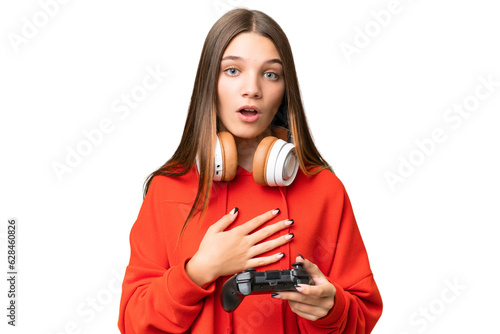 Teenager caucasian girl playing with a video game controller over isolated background surprised and shocked while looking right