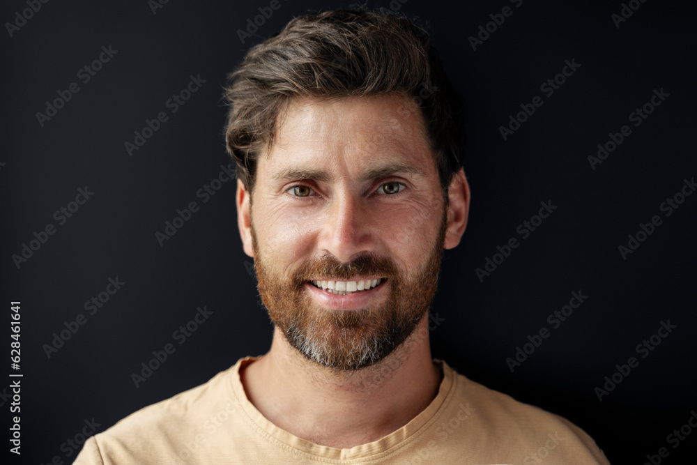 Fototapeta premium Closeup portrait of handsome smiling latin man looking at camera isolated on black background. Happy bearded hipster after barbershop service