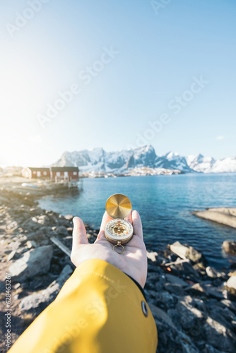 Unrecognizable person with compass in hand near seawater photo