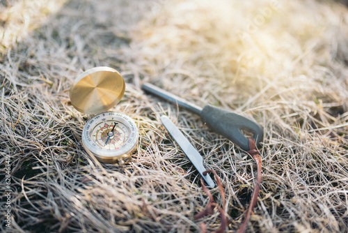 Easy to carry vintage compass with mini fire steel and striker placed on dry grass in daylight photo