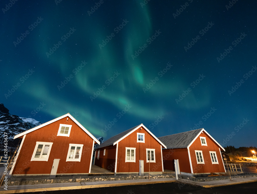Amazing view of northern lights over red wooden houses and snowy ...