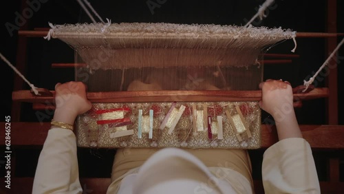 Top down weaver weaving a piece of pua kumbu traditonal fabric on a loom in dramatic lighting photo