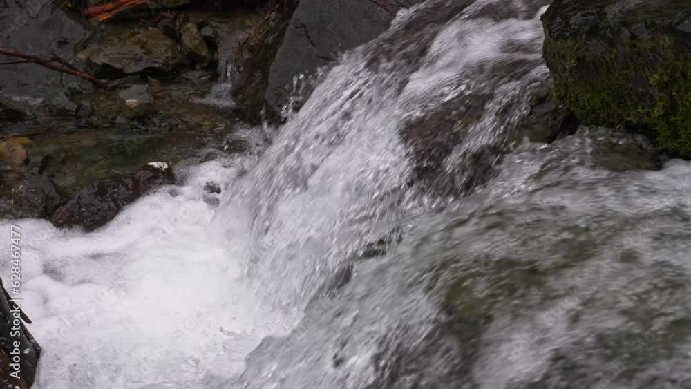 A stormy stream of a mountain stream flows through the stones. Pure water in a mountain stream is formed due to the melting of snow. A stormy stream of a mountain stream flows through the stones. Pure water in a mountain stream is formed due to the melting of snow.