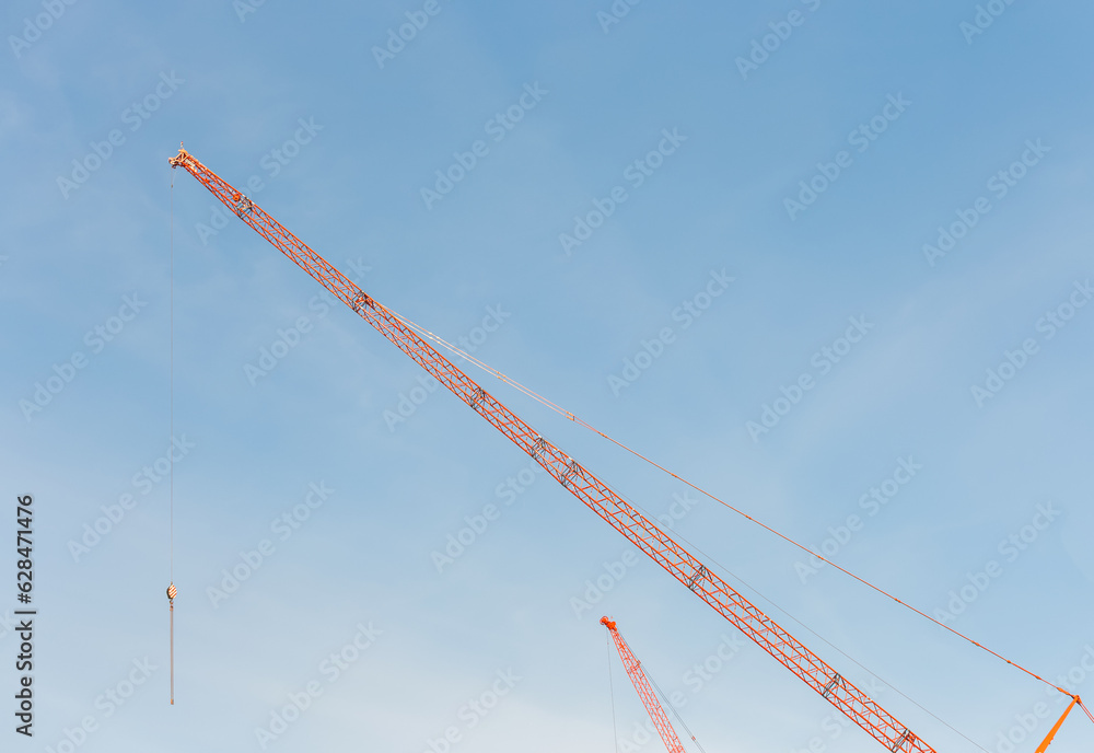 Construction site. Construction cranes and a building under construction against a blue sky background. Construction site. Construction cranes and a building under construction against a blue sky background.
