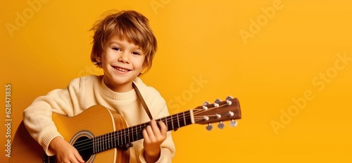 Joyful child playing guitar isolated on flat orange background with copy space. Creative banner for children's music school.