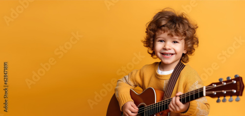 Joyful child playing guitar isolated on flat orange background with copy space. Creative banner for children's music school.