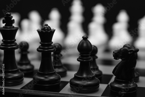 Black and White chess pieces with focus on black pieces and white unfocused on the background. Close up photo
