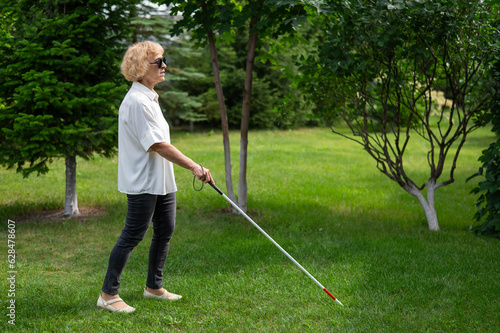 Elderly blind woman walking in the park. 