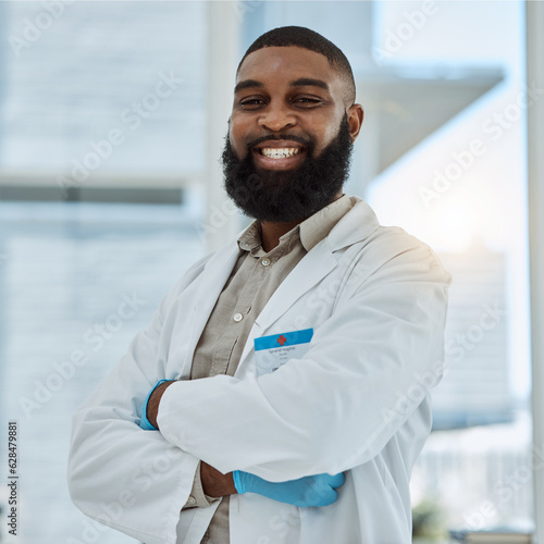 Black man  doctor and portrait with arms crossed in hospital for healthcare services  surgery and consulting in Nigeria. Happy surgeon  therapist and medical professional working with trust in clinic