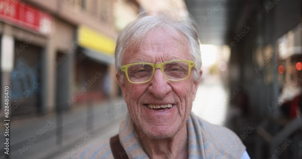 Senior man smiling in front of camera while waiting at tram station in the city Senior man smiling in front of camera while waiting at tram station in the city