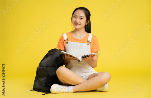 beautiful asian schoolgirl posing on a yellow background