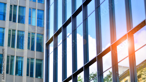 Structural glass wall reflecting blue sky. Abstract modern architecture fragment. Glass building with transparent facade of the building and blue sky. Contemporary architectural background.