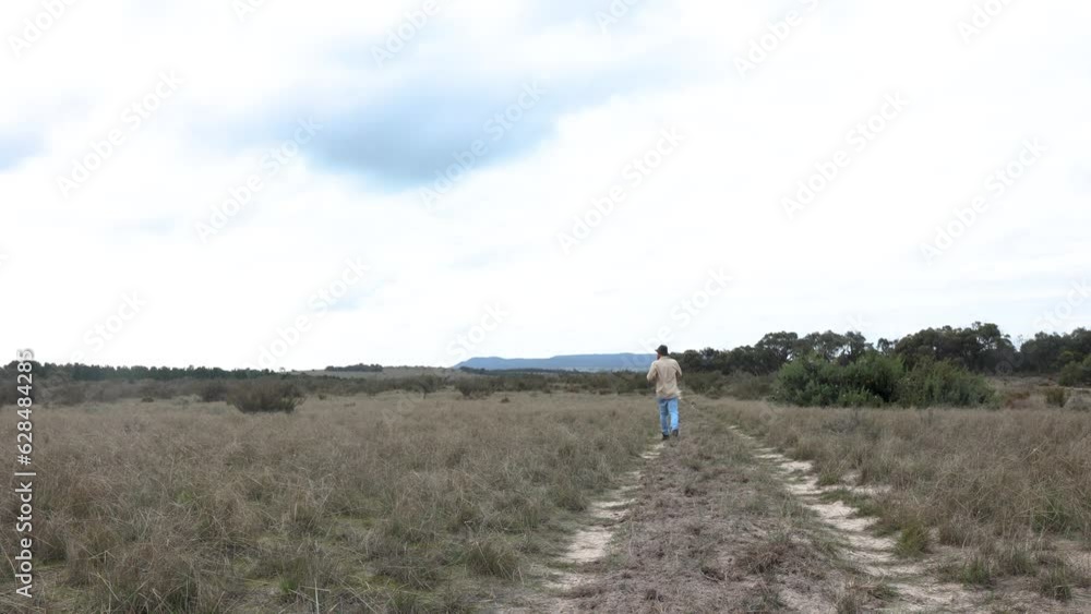 A bushman runs with his border collie dog in the Australian desert down a remote dirt track. A bushman runs with his border collie dog in the Australian desert down a remote dirt track.