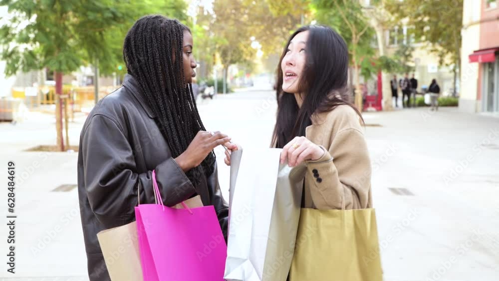 Happy beautiful women looking inside shopping bag and smiling at city outdoors . Fashion girl showing something to her friend in a shopping day Happy beautiful women looking inside shopping bag and smiling at city outdoors . Fashion girl showing something to her friend in a shopping day