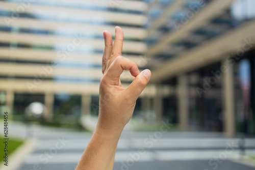 Female hand doing ok sign with fingers, excellent symbol on blurred business center background. High quality photo