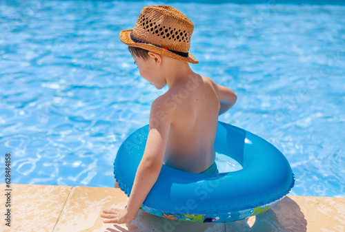 cute boy with beach sunny hat swimming in pool with inflatable ring tube.smiling adorable boy clean brite blu water summer vacation