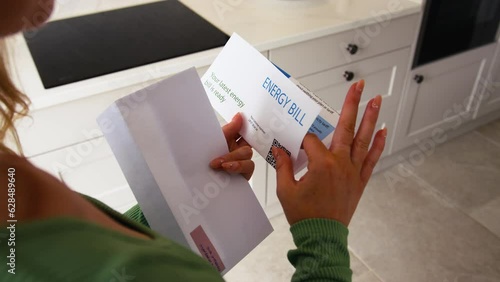 Close up of woman at home opening American dollar energy bill during cost of living crisis - shot in slow motion photo