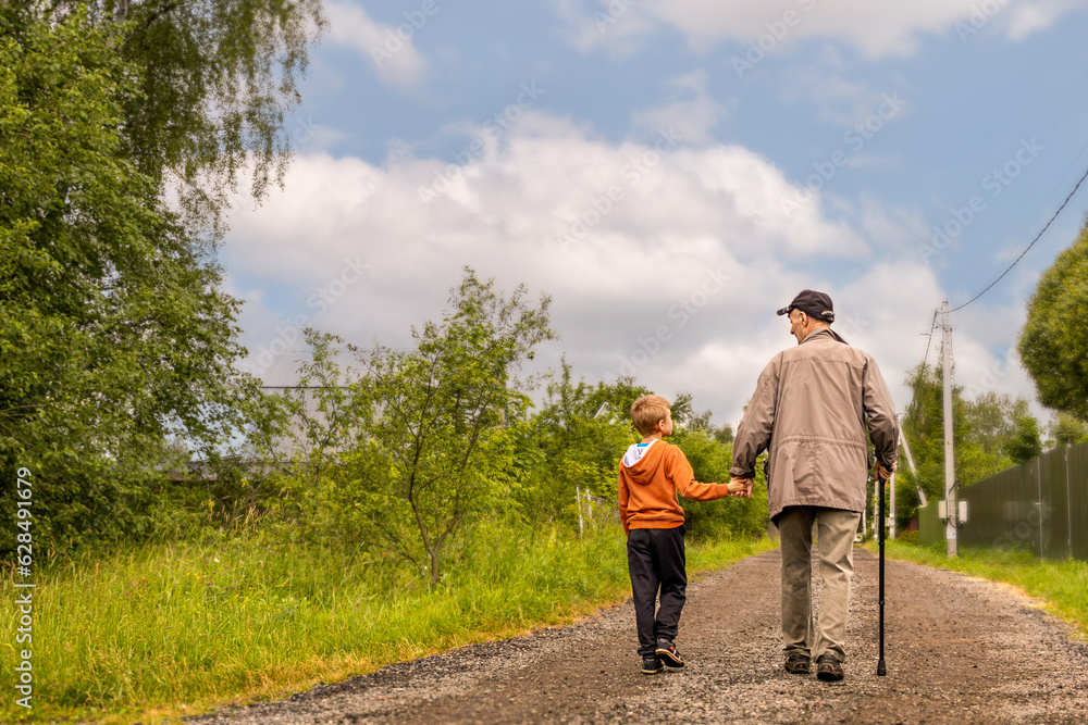 grandfather and grandson are walking down road and having conversation on sunny summer day. Copy space grandfather and grandson are walking down road and having conversation on sunny summer day. Copy space