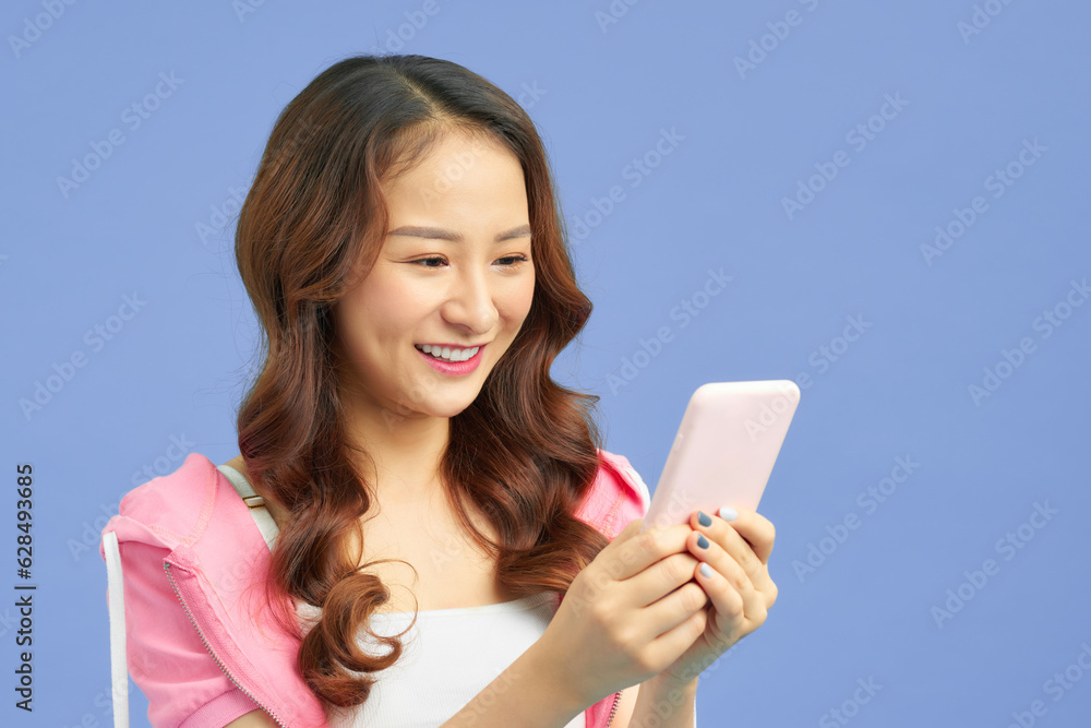 attractive asian woman using smart phone isolated on blue background attractive asian woman using smart phone isolated on blue background