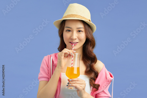 Young beautiful woman on vacation wearing summer hat drinking orange juice