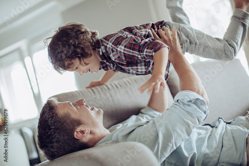 Father and son playing on the couch in the living room at home