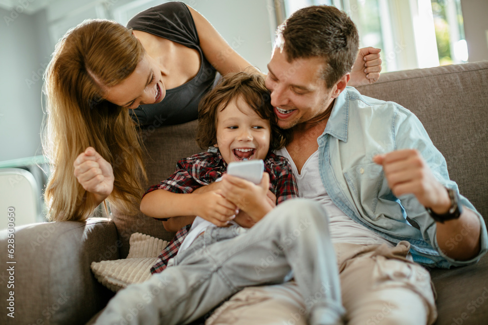 Young family using a smart phone while sitting on the couch in the living room