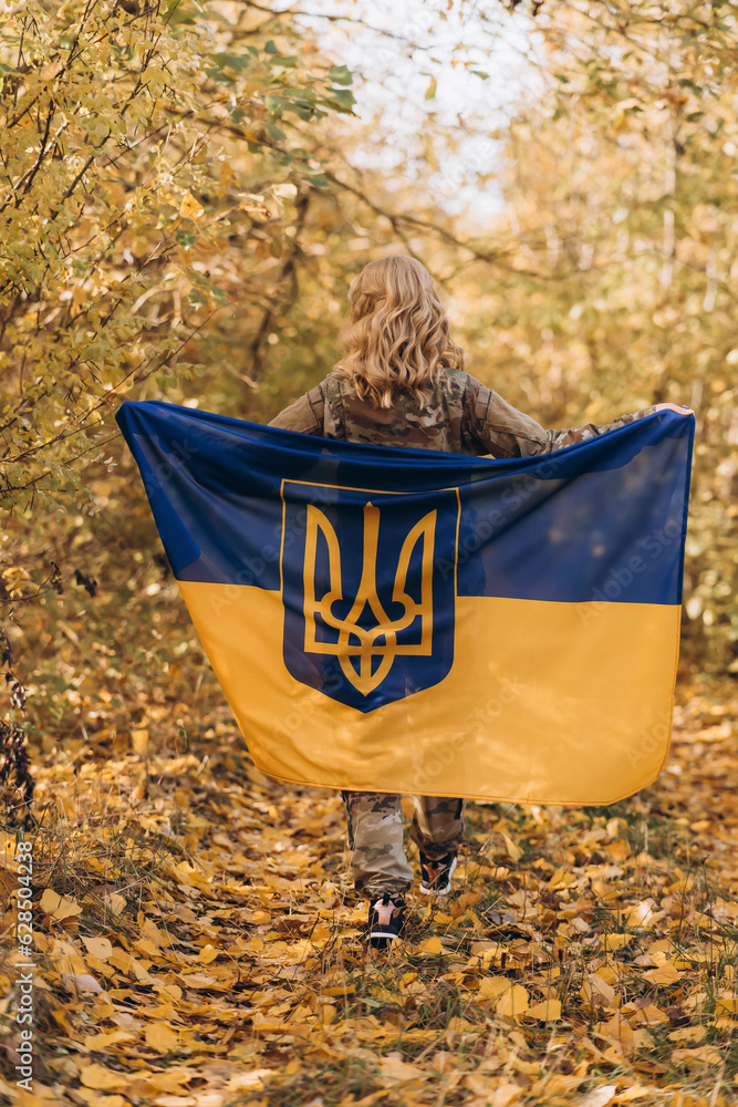 Obraz premium A beautiful Ukrainian woman with a Ukrainian flag on her shoulders.