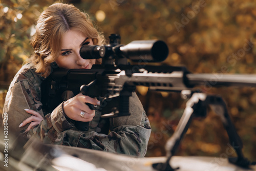 A female soldier fires a rifle from the hood of a pickup truck. War, army, military concept.