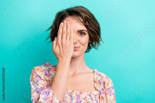 Photo of optimistic pleasant cute woman with short hairstyle wear colorful top arm cover eye isolated on turquoise color background