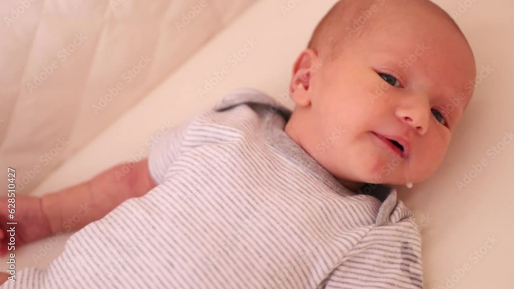 A small newborn baby is lying in bed, regurgitating milk. The baby burped in bed A small newborn baby is lying in bed, regurgitating milk. The baby burped in bed