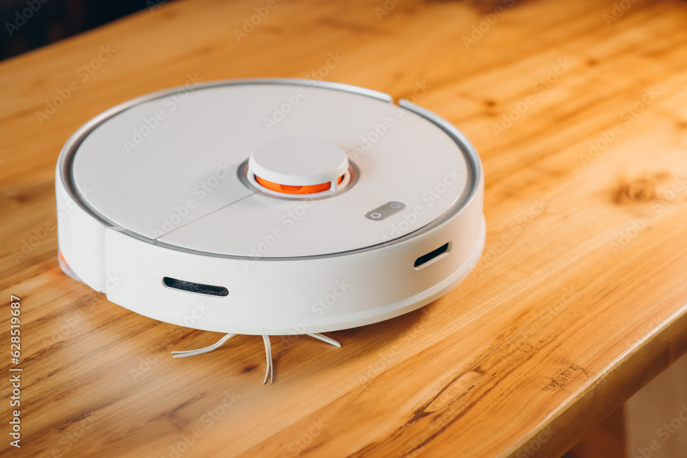 Robot vacuum cleaner on a wooden floor. View from the side. Smart home. The concept of a home assistant. Robot vacuum cleaner on a wooden floor. View from the side. Smart home. The concept of a home assistant.