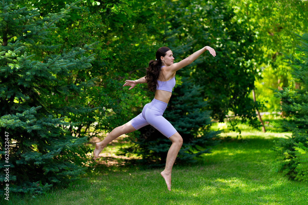 young fit woman jump in the air outdoors on a grass field young fit woman jump in the air outdoors on a grass field