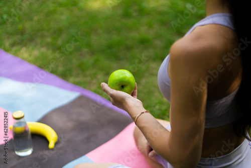 woman holding a fresh fruit during outdoors yoga class