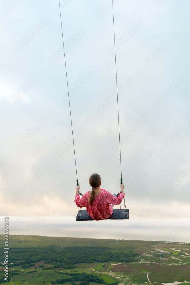 Little girl is on a swing under cloudy sky. Montana Redonda