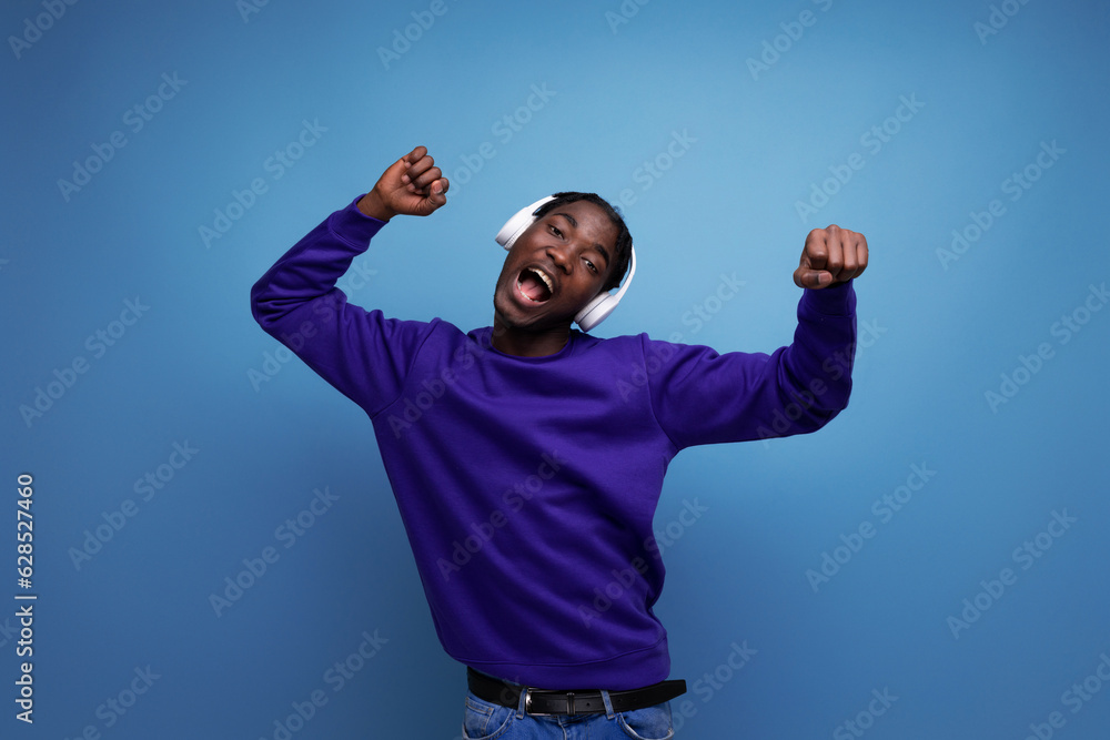 Naklejka premium american young man with dreadlocks dancing to music with headphones