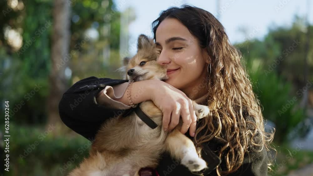Young hispanic woman with dog smiling kissing at park Young hispanic woman with dog smiling kissing at park