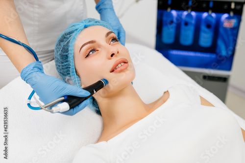 Beauty therapist performing hydrafacial procedure on woman