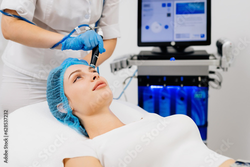 Beauty therapist performing hydrafacial procedure on woman