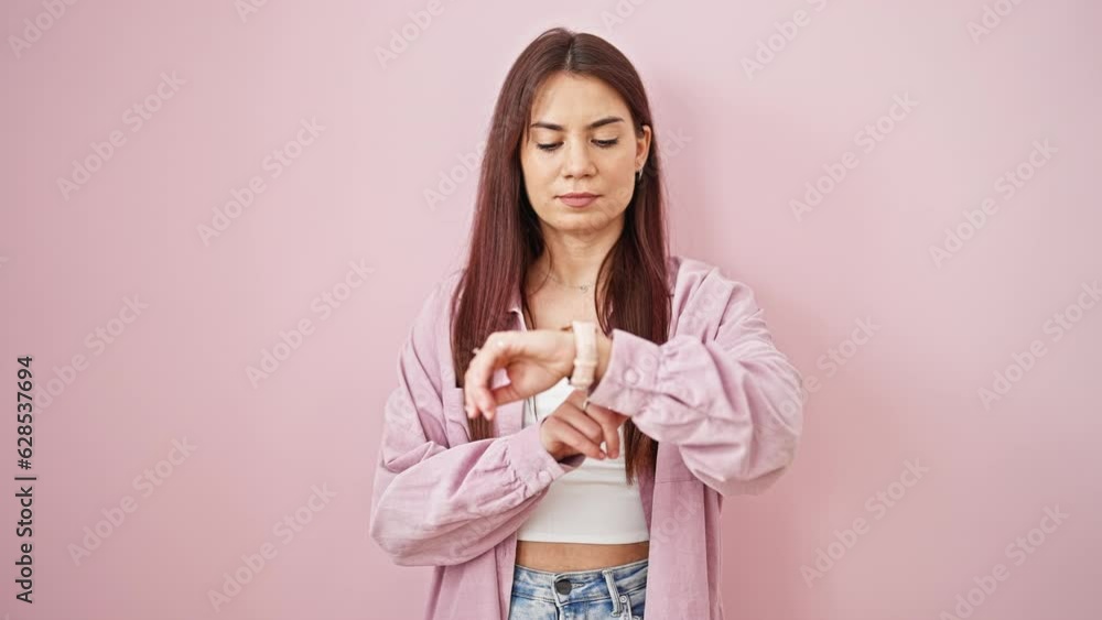 Young beautiful hispanic woman looking watch saying no with head over isolated pink background Young beautiful hispanic woman looking watch saying no with head over isolated pink background