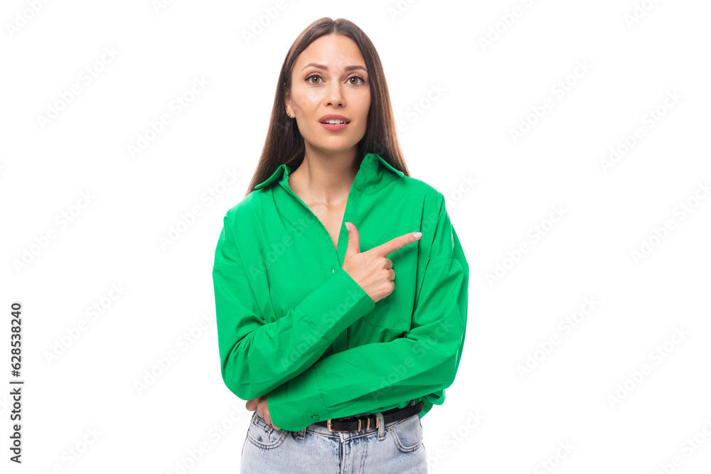 surprised young brown-eyed brown-haired woman in a green blouse points her finger to the side surprised young brown-eyed brown-haired woman in a green blouse points her finger to the side