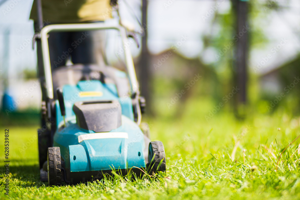 Lawn mover on green grass in modern garden or backyard. Machine for cutting lawns. Gardening care tools and equipment Lawn mover on green grass in modern garden or backyard. Machine for cutting lawns. Gardening care tools and equipment