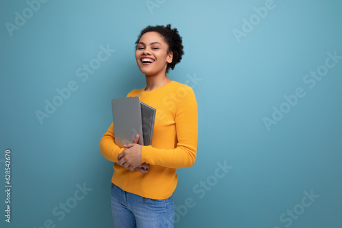 successful young 25 year old hispanic lady student with afro tail holding a laptop in her hands