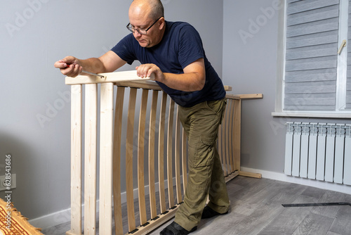 A man is assembling a new wooden bed in the room.