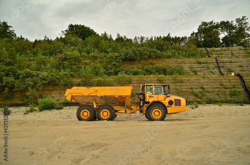 Canvas-taulu large truck dumb earth moving on the desert beside cliffs sea walls