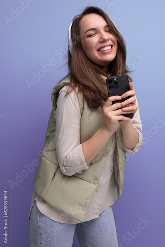 cheerful young lady brunette dances listening to music in headphones on a studio background