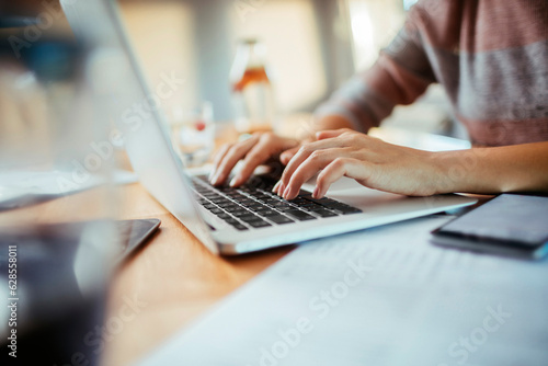 Young woman working on her laptop at home and going over her bills