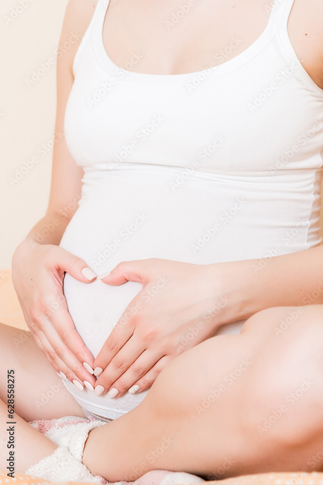 happy pregnant woman making heart in home on bed. Pregnancy, love and expectation concept